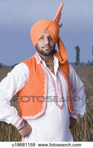 Stock Photo - Portrait of a young man standing in a wheat field. Fotosearch