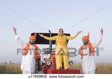 Stock Image - Portrait of a young woman with two young men dancing on a tractor. Fotosearch