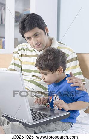 Boy using a laptop with his father View Large Photo Image Stock Photography - Boy using a laptop with his father. Fotosearch