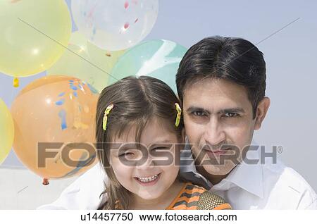 Close-up of a mid adult man smiling with his daughter View Large Photo Image Stock Image - Close-up of a mid adult man smiling with his daughter. Fotosearch