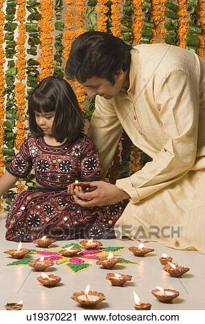 Stock Image - Mid adult man and his daughter holding an oil lamp. Fotosearch