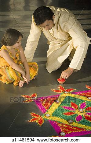 Mid adult man making a rangoli with his daughter View Large Photo Image Picture - Mid adult man making a rangoli with his daughter. Fotosearch
