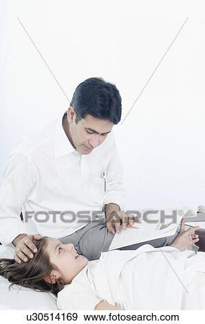 Mid adult man reading a book beside his daughter lying on the bed View Large Photo Image Stock Photo - Mid adult man reading a book beside his daughter lying on the bed. Fotosearch