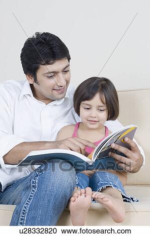 Mid adult man reading a book with his daughter View Large Photo Image Stock Image - Mid adult man reading a book with his daughter. Fotosearch