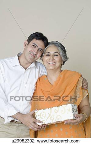 Portrait of a mature woman and her son holding a gift and smiling View Large Photo Image Stock Image - Portrait of a mature woman and her son holding a gift and smiling. Fotosearch