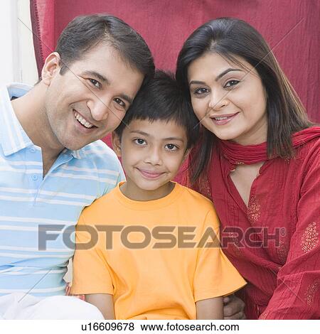 Stock Photo - Portrait of a mid adult couple sitting with their son and smiling. Fotosearch