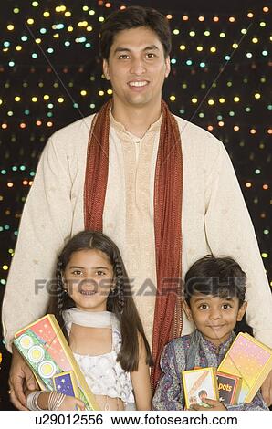 Portrait of a young man standing with his son and daughter and holding diwali crackers View Large Photo Image Stock Photograph - Portrait of a young man standing with his son and daughter and holding diwali crackers. Fotosearch