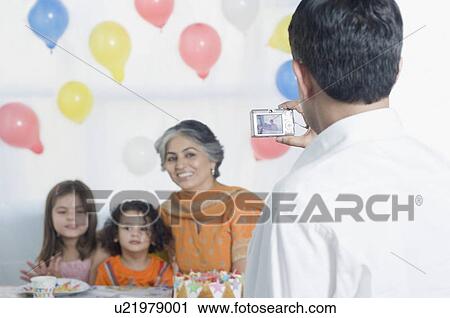 Rear view of a mid adult man taking a picture of a mature woman and her grandchildren View Large Photo Image Stock Image - Rear view of a mid adult man taking a picture of a mature woman and her grandchildren. Fotosearch