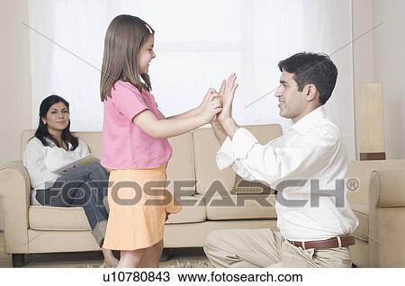 Stock Image - Side profile of a mid adult man playing clapping game with his daughter. Fotosearch