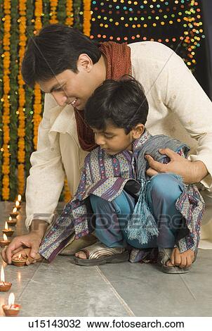 Young man lighting diwali lamps with his son View Large Photo Image Stock Image - Young man lighting diwali lamps with his son. Fotosearch