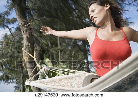 Low angle view of a young woman sitting in a hammock and stretching View Large Photo Image Stock Image - Low angle view of a young woman sitting in a hammock and stretching. Fotosearch
