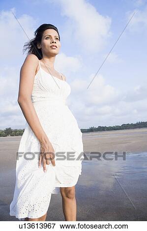 Low angle view of a young woman standing on the beach View Large Photo Image Stock Photo - Low angle view of a young woman standing on the beach. Fotosearch