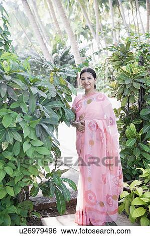 Mature woman standing in a garden View Large Photo Image Stock Photograph - Mature woman standing in a garden. Fotosearch