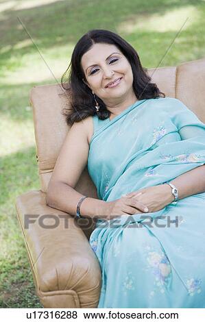 Portrait of a mid adult woman sitting in an armchair in a park View Large Photo Image Stock Photo - Portrait of a mid adult woman sitting in an armchair in a park. Fotosearch