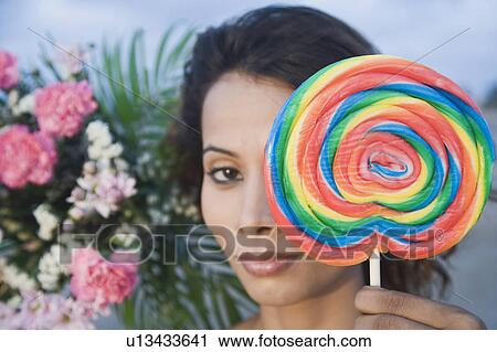Stock Image - Portrait of a young woman holding a candy. Fotosearch