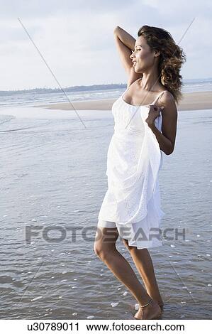 Side profile of a young woman standing on the beach and looking away View Large Photo Image Stock Image - Side profile of a young woman standing on the beach and looking away. Fotosearch