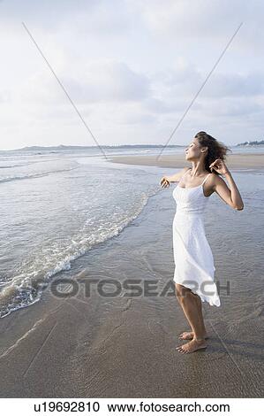 Stock Image - Side profile of a young woman stretching on the beach. Fotosearch