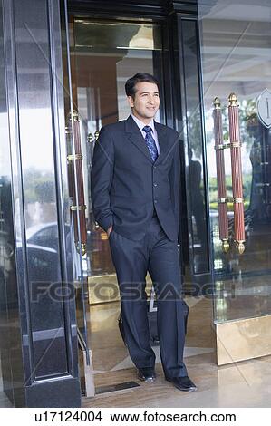 Picture - Businessman pulling his luggage at the door of a hotel. Fotosearch
