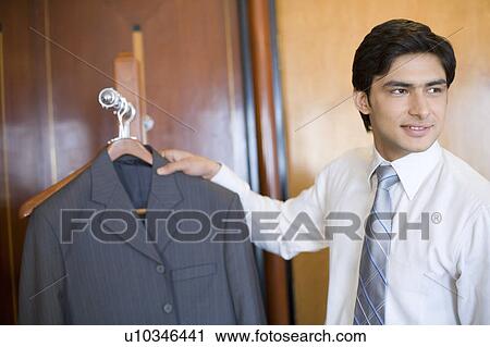 Close-up of a businessman holding a business suit and smiling View Large Photo Image Stock Image - Close-up of a businessman holding a business suit and smiling. Fotosearch