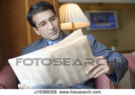 Close-up of a businessman sitting in an armchair and reading a newspaper View Large Photo Image Stock Photo - Close-up of a businessman sitting in an armchair and reading a newspaper. Fotosearch