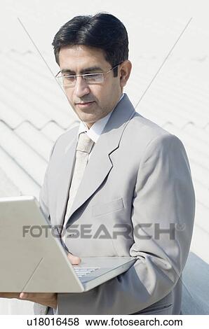 Close-up of a businessman working on a laptop View Large Photo Image Stock Photo - Close-up of a businessman working on a laptop. Fotosearch