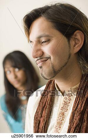 Stock Photograph - Close-up of a young man smiling with his sister in the background. Fotosearch