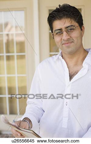 Mid adult man smiling and holding a magazine View Large Photo Image Stock Photography - Mid adult man smiling and holding a magazine. Fotosearch