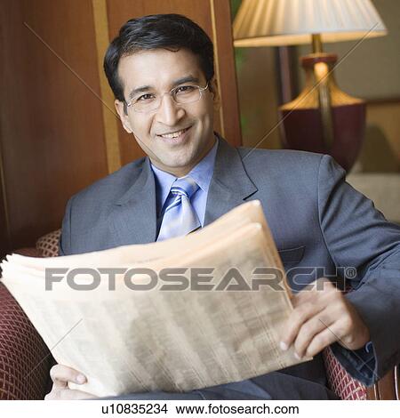 Portrait of a businessman holding a newspaper and smiling View Large Photo Image Picture - Portrait of a businessman holding a newspaper and smiling. Fotosearch