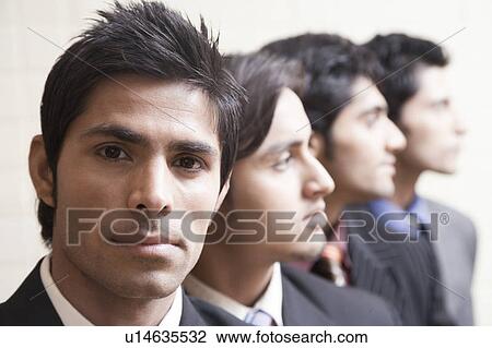 Stock Image - Portrait of a businessman looking serious with three business executives behind him. Fotosearch