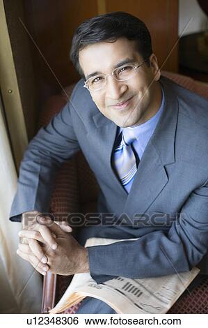 Portrait of a businessman sitting in an armchair and smiling View Large Photo Image Stock Photograph - Portrait of a businessman sitting in an armchair and smiling. Fotosearch