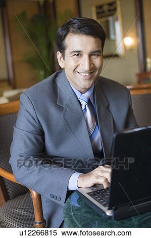 Portrait of a businessman using a laptop and smiling View Large Photo Image Stock Photography - Portrait of a businessman using a laptop and smiling. Fotosearch
