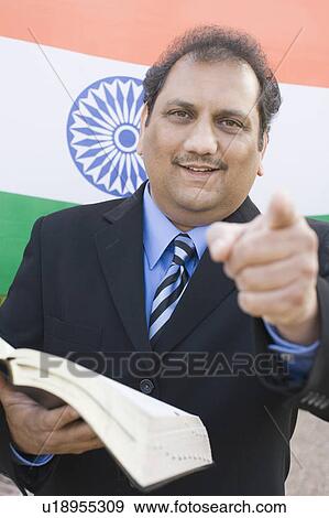 Stock Photo - Portrait of a mature man holding a book and pointing forward. Fotosearch