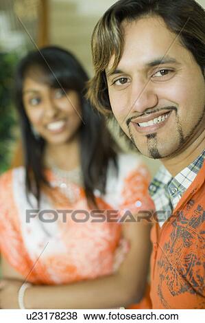 Stock Photo - Portrait of a young man smiling with a teenage girl standing beside him. Fotosearch