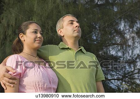 Close-up of a mid adult man standing with his arm around a mid adult woman View Large Photo Image Stock Image - Close-up of a mid adult man standing with his arm around a mid adult woman. Fotosearch