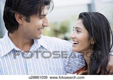 Stock Photo - Close-up of a young couple looking at each other and smiling. Fotosearch