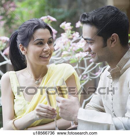 Stock Photograph - Close-up of a young couple smiling and toasting with champagne flutes. Fotosearch
