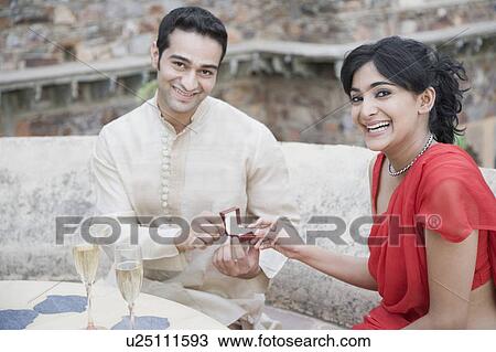 Close-up of a young man giving an engagement ring to a young woman View Large Photo Image Stock Image - Close-up of a young man giving an engagement ring to a young woman. Fotosearch