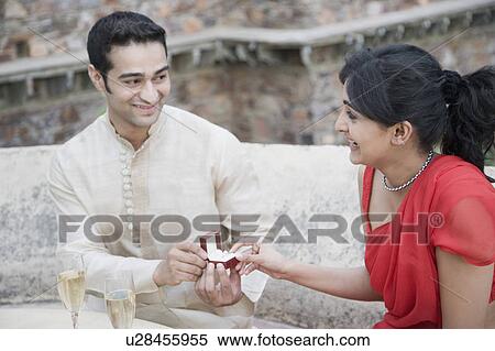 Close-up of a young man giving an engagement ring to a young woman View Large Photo Image Stock Photography - Close-up of a young man giving an engagement ring to a young woman. Fotosearch