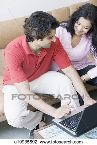 High angle view of a young couple using a laptop View Large Photo Image Stock Image - High angle view of a young couple using a laptop. Fotosearch