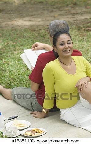 Mid adult couple sitting back to back in a park View Large Photo Image Stock Image - Mid adult couple sitting back to back in a park. Fotosearch