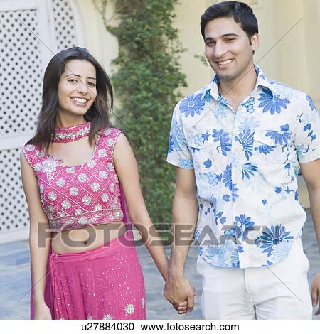 Portrait of a young couple holding hands of each other and walking View Large Photo Image Stock Image - Portrait of a young couple holding hands of each other and walking. Fotosearch