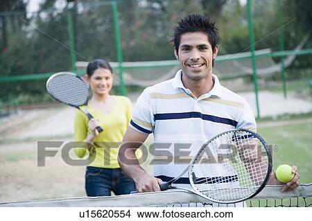 Portrait of a young couple standing in a tennis court View Large Photo Image Picture - Portrait of a young couple standing in a tennis court. Fotosearch