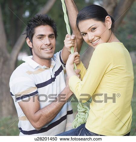 Portrait of a young couple swinging on a tire swing and smiling View Large Photo Image Stock Image - Portrait of a young couple swinging on a tire swing and smiling. Fotosearch