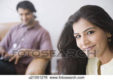Portrait of a young woman smiling with a young man sitting in the background View Large Photo Image Stock Photograph - Portrait of a young woman smiling with a young man sitting in the background. Fotosearch