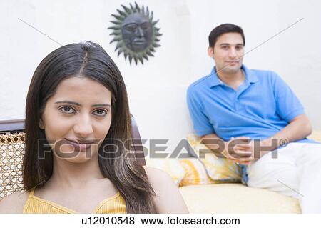 Portrait of a young woman with a young man sitting behind her View Large Photo Image Stock Photo - Portrait of a young woman with a young man sitting behind her. Fotosearch