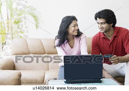 Young couple shopping online with a credit card and looking at each other View Large Photo Image Picture - Young couple shopping online with a credit card and looking at each other. Fotosearch