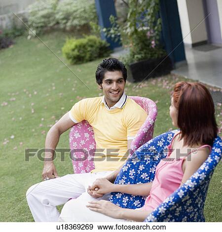 Young couple sitting in a lawn and smiling View Large Photo Image Stock Photo - Young couple sitting in a lawn and smiling. Fotosearch