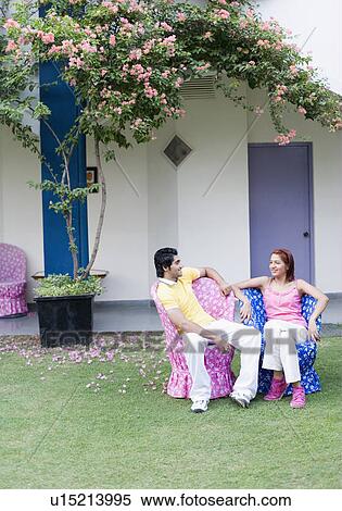 Young couple sitting in a lawn and smiling View Large Photo Image Stock Photography - Young couple sitting in a lawn and smiling. Fotosearch