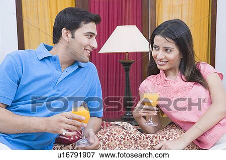 Young couple smiling and holding glasses of fruit juice View Large Photo Image Stock Photo - Young couple smiling and holding glasses of fruit juice. Fotosearch