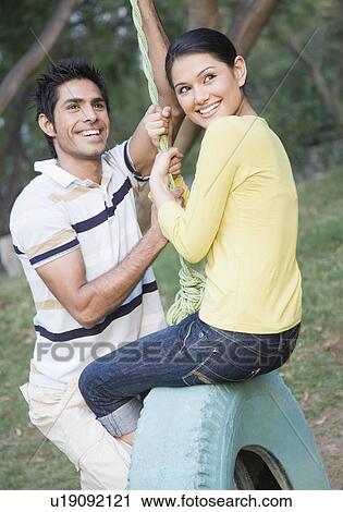 Young couple swinging on a tire swing View Large Photo Image Stock Image - Young couple swinging on a tire swing. Fotosearch